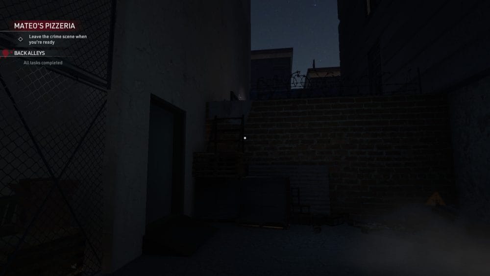 Back alleyway with a brick wall and a step ladder piled on top of a pallet.