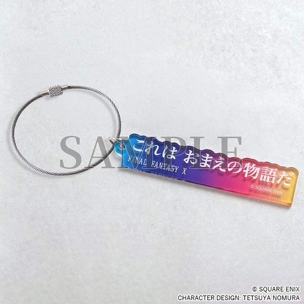 An blue/pink/yellow acrylic keychain with white Japanese text.