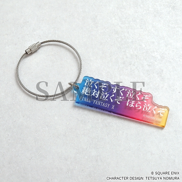 An blue/pink/yellow acrylic keychain with white Japanese text.