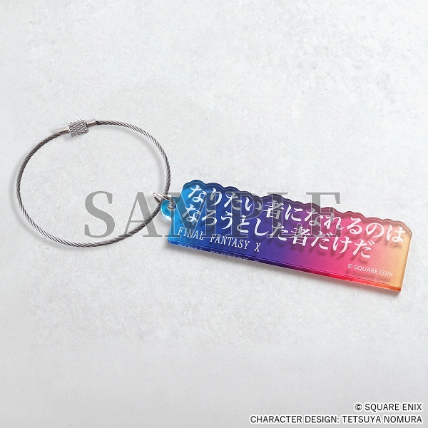 An blue/pink/yellow acrylic keychain with white Japanese text.