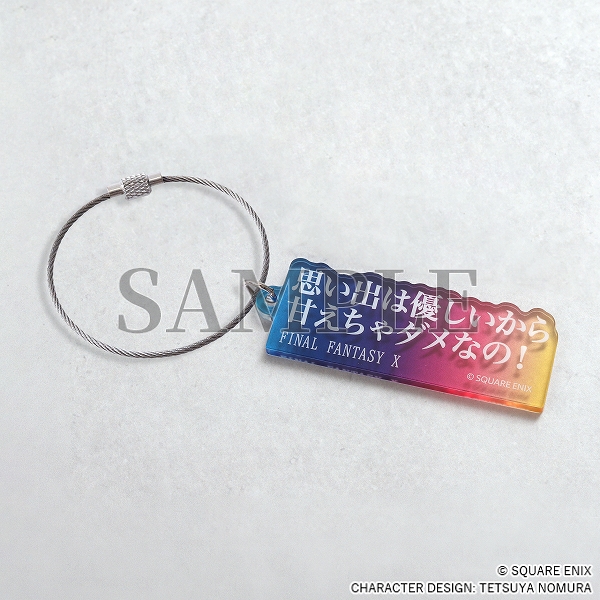 An blue/pink/yellow acrylic keychain with white Japanese text.