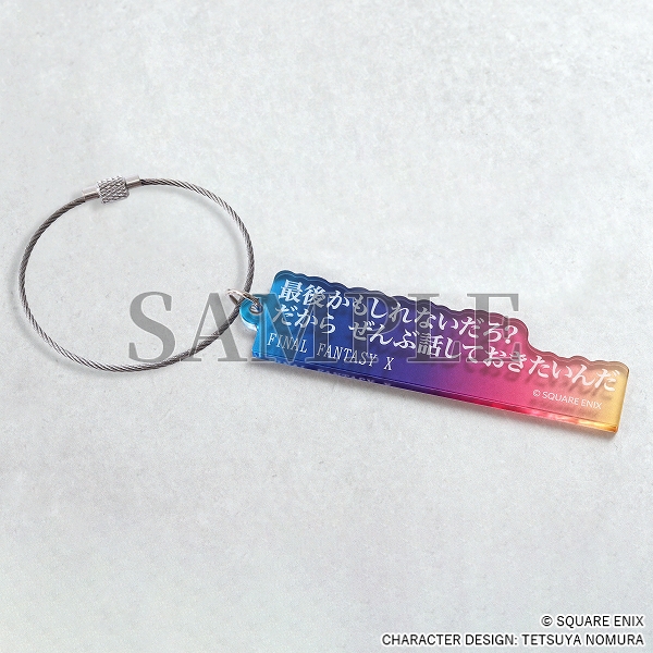 An blue/pink/yellow acrylic keychain with white Japanese text.