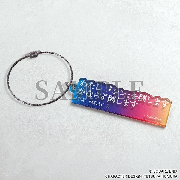 An blue/pink/yellow acrylic keychain with white Japanese text.