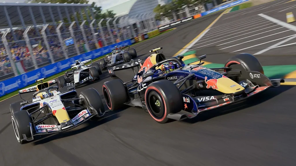 Several F1 cars race towards the screen, taking a corner at high speed, crowds of fans stand behind high fences in the background is partially blurred